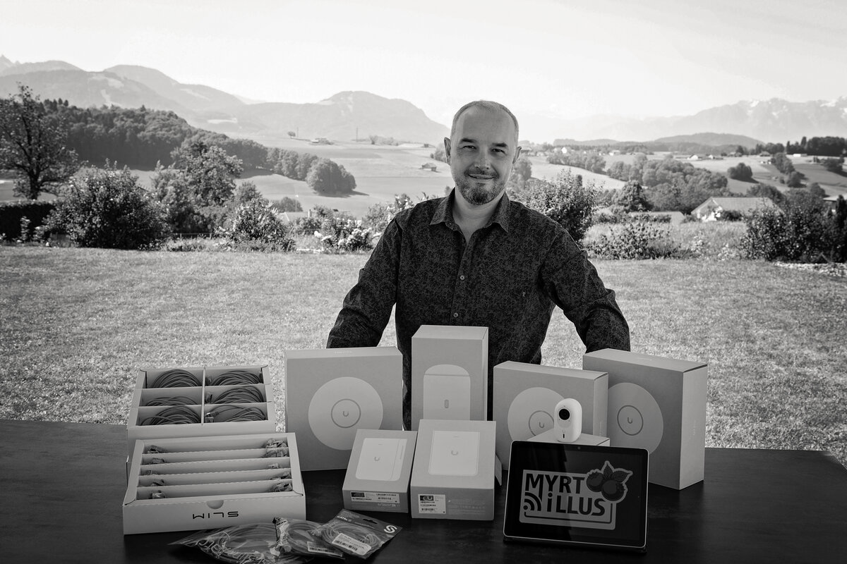 Gregory Huber, fondateur de Myrtillus, avec son matériel réseau UniFi devant les Alpes suisses